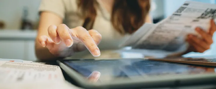 woman holding papers and working on a tablet tax preparation